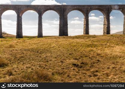 Arches against blue sky and cloud of the Ribblehead Viaduct, landscape. North Yorkshire, Europe, England, landscape and telephoto.