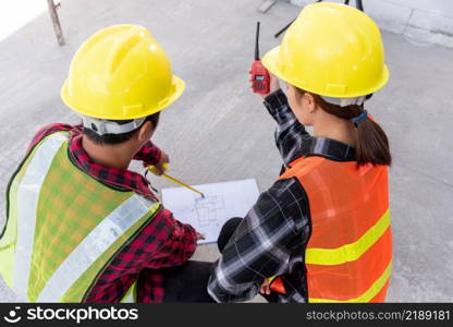 Architect and client discuss help create plan with blueprint of the building at construction site floor. Asian engineer foreman worker man and woman meeting talking on drawing paper project, top view