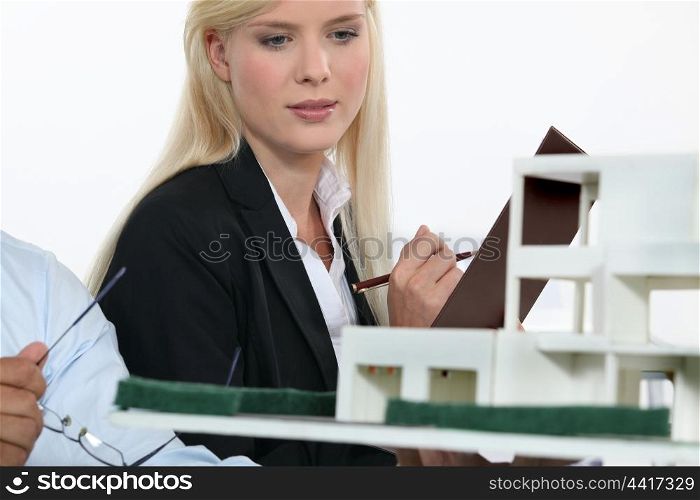 Architect and co-worker looking at model building