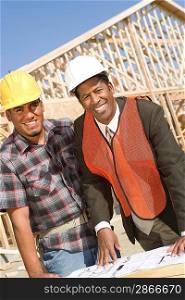 Architect and construction worker leaning to table with blueprints