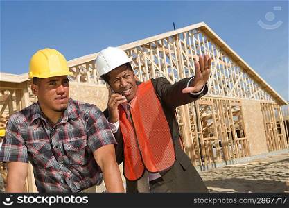 Architect and construction worker leaning to table with blueprints
