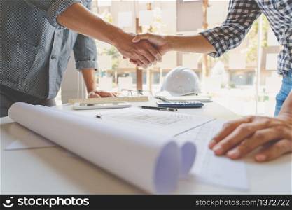Architect and engineer construction workers shaking hands while working for teamwork and cooperation concept after finish an agreement in the office construction site, success collaboration concept