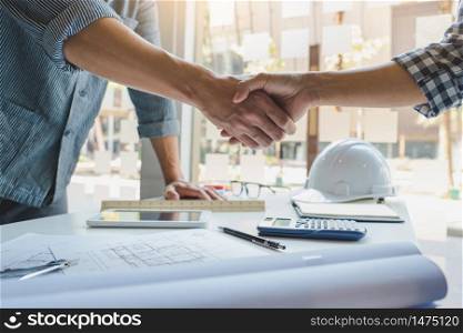 Architect and engineer construction workers shaking hands while working for teamwork and cooperation concept after finish an agreement in the office construction site, success collaboration concept