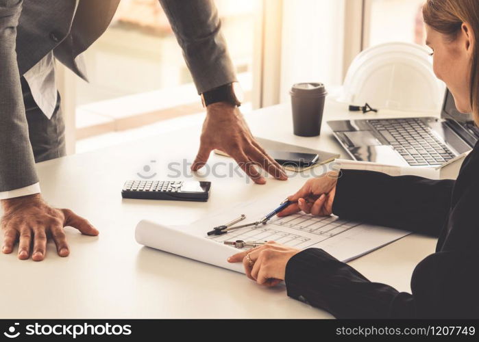 Architect and engineer working with construction drawing project on table in office. Architecture and engineering business concept.. Architect and engineer working with drawing.