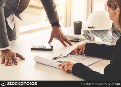 Architect and engineer working with construction drawing project on table in office. Architecture and engineering business concept.. Architect and engineer working with drawing.