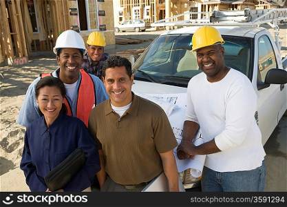 Architect and four construction workers standing in front of car on construction site