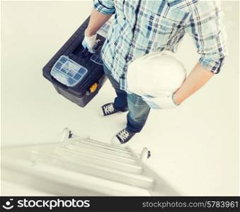 architect and home renovation concept - man with ladder, helmet and toolkit