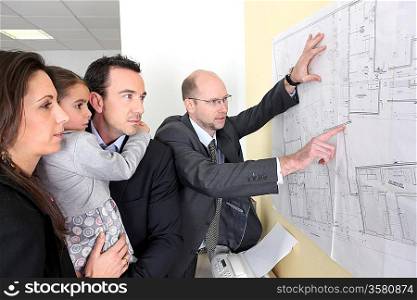 Architect checking plans stuck to office wall