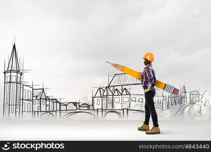 Architect female designer. Young female engineer in hard hat with big pencil and buildings sketches at background