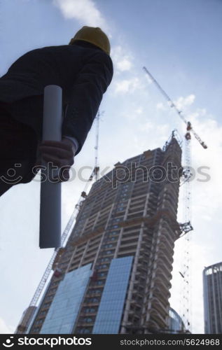 Architect holding blue print and looking up, low angle view