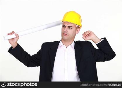 architect holding blueprints stretching himself against studio background