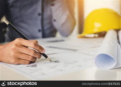 Architect holding pencil and pointing on blueprint.