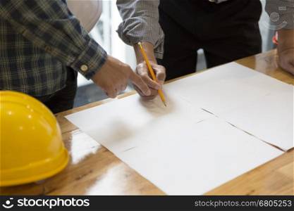 architect holding pencil working on blueprint of construction project in workplace