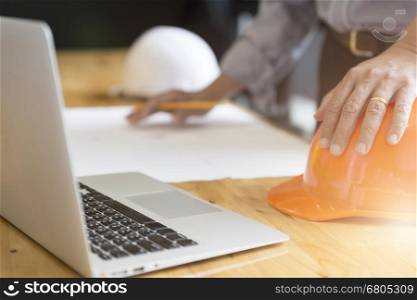 architect holding pencil working on blueprint of construction project in workplace with computer on office desk