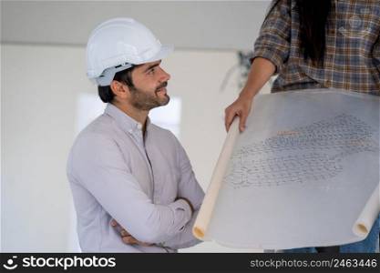 Architect in white helmets reviewing blueprints at a construction site.
