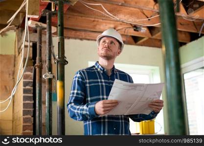 Architect Inside House Being Renovated Studying Plans