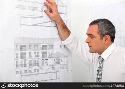 Architect looking at blueprints stuck to wall