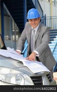 Architect looking at plans on a car bonnet