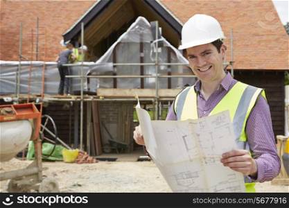 Architect On Building Site Looking At House Plans