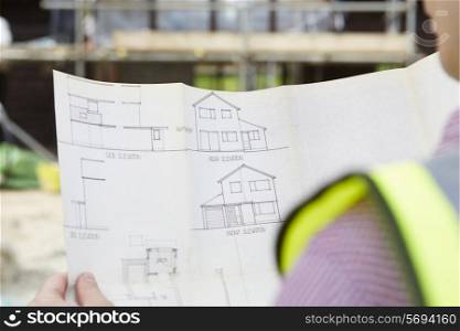 Architect On Building Site Looking At Plans For House