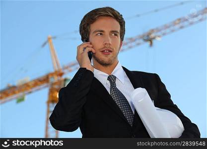 Architect on site with plans and cellphone