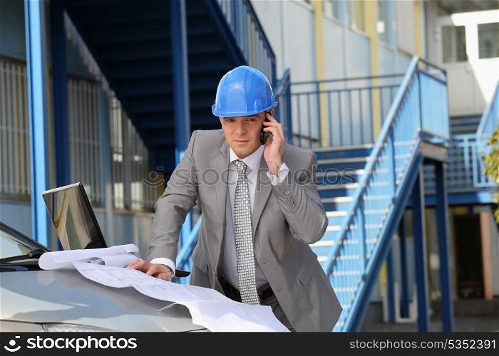 Architect on site with plans and cellphone