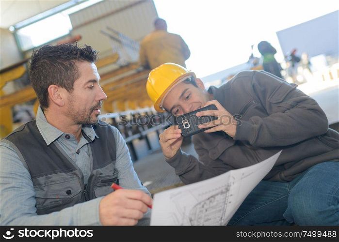 architect taking a photo of blueprint with mobile phone