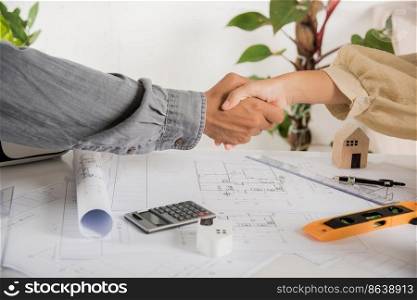 Architect team success and handshaking after meeting consult and work for architectural construction project with partner editing on blueprint paper plans, Architect and engineer shaking hands