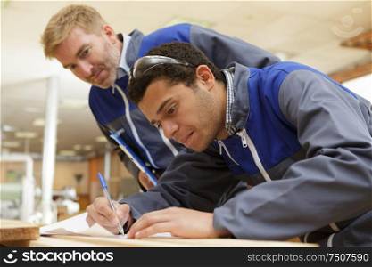 architect with architectural drawing and apprentice