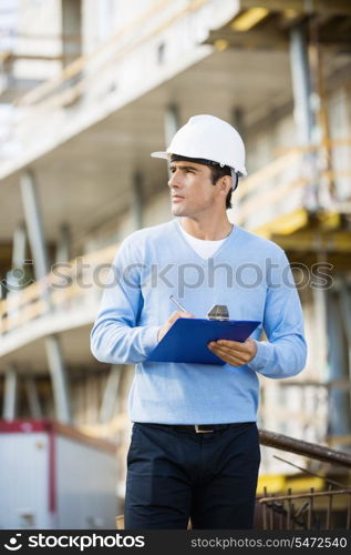 Architect with clipboard and pen working at construction site