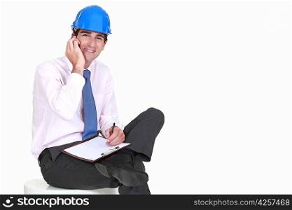 Architect with clipboard making telephone call