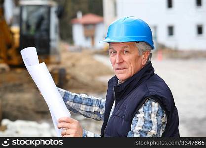 Architect with drawing on construction site