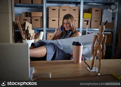 Architect woman in office warehouse talking mobile phone with paper project plan
