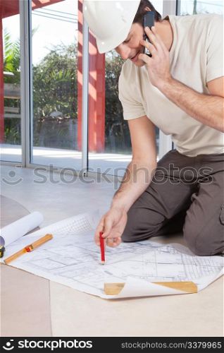 Architect working on blueprint and talking on cellphone