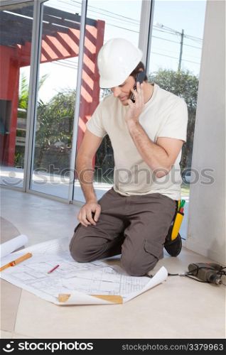 Architect working on blueprint while talking on cellphone