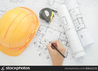 Architect working on construction blueprint. Architects workplace - architectural project, blueprints, helmet, measuring tape, Construction concept. Engineering tools. Top view