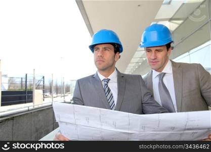 Architects checking construction site with plan outside