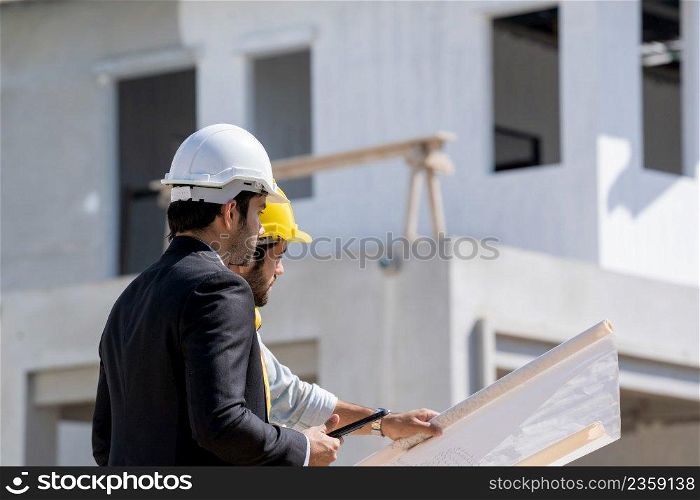Architects discuss with head engineer about construction project on workplace at construction site.