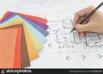 architects hands drawing of modern house with colors and material samples on creative desk