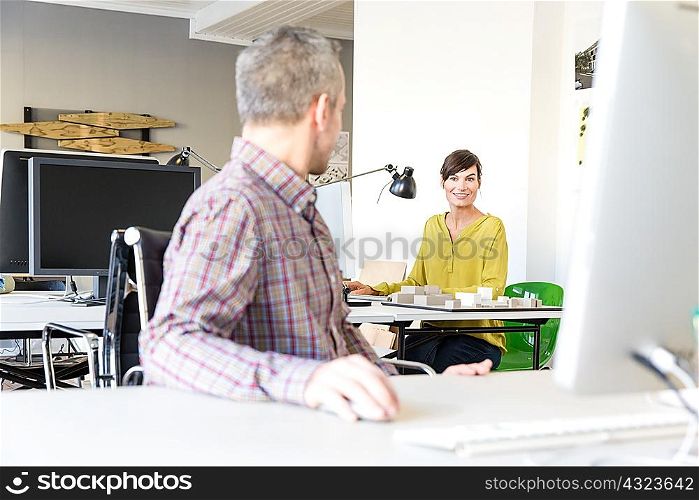 Architects in office using computer, talking and smiling