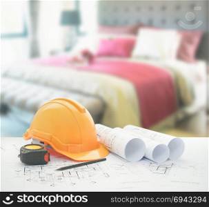 architectural blueprint with safety helmet and tools over bedroom with red scheme color decoration