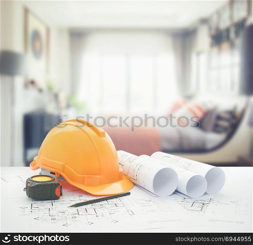 architectural blueprint with safety helmet and tools over modern bedroom interior