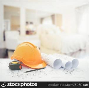 architectural blueprint with safety helmet and tools over modern bedroom interior