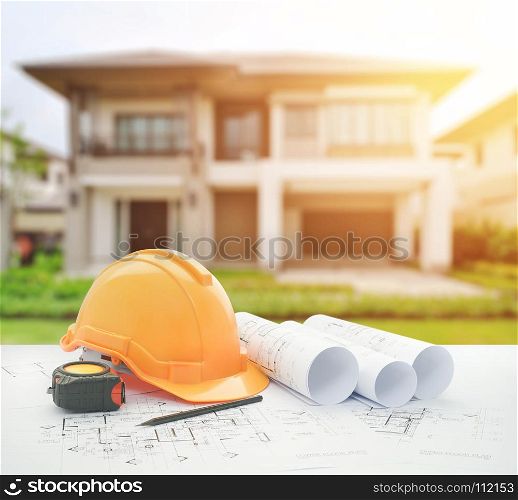 architectural blueprint with safety helmet and tools over modern building as background