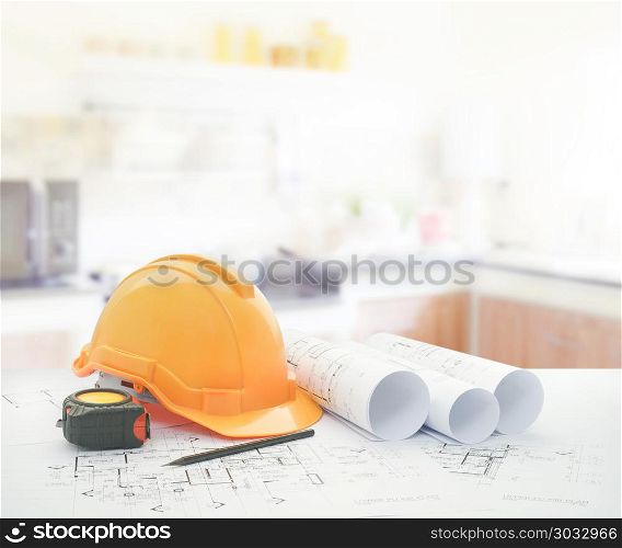 architectural blueprint with safety helmet and tools over modern kitchen interior. architectural blueprint with safety helmet and tools over modern