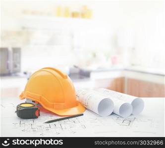 architectural blueprint with safety helmet and tools over modern kitchen interior. architectural blueprint with safety helmet and tools over modern