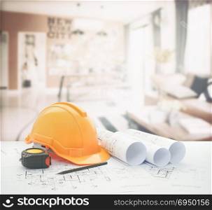 architectural blueprint with safety helmet and tools over modern living corner next to the dining room