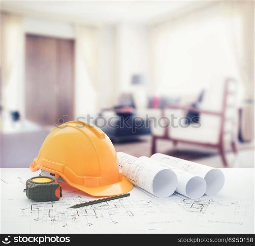 architectural blueprint with safety helmet and tools over modern living room interior