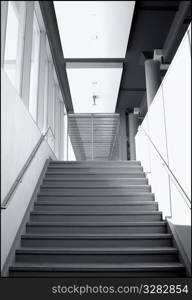 Architectural composition of converging stairs, walls and windows.