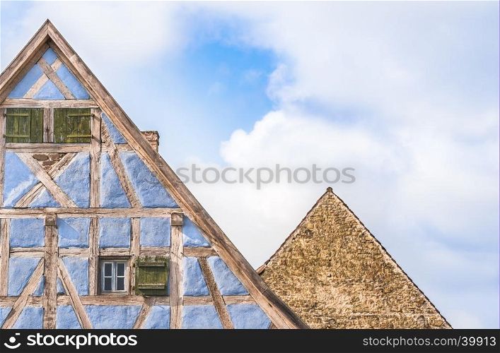 Architectural details of two lofts from medieval german houses, one with half timbered blue walls, wooden shutters and one with stone wall.